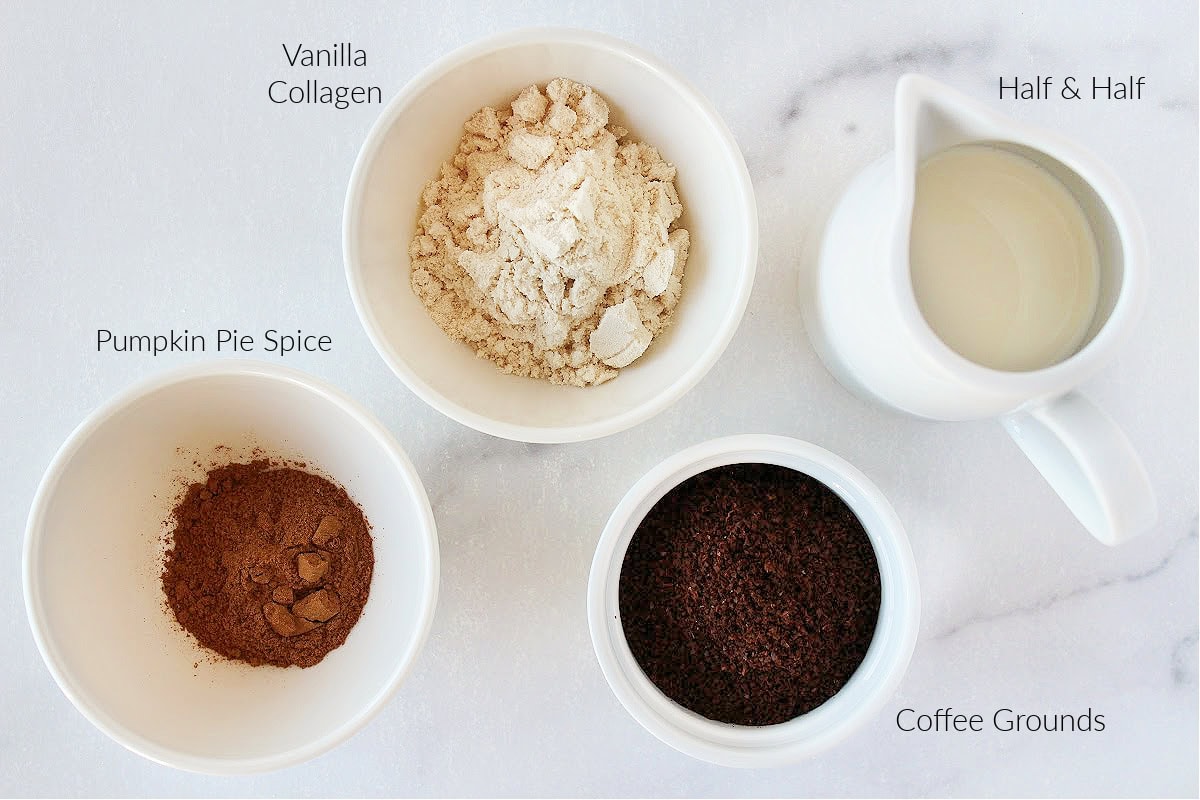 Labeled ingredients for homemade pumpkin spice latte on a white marble countertop.