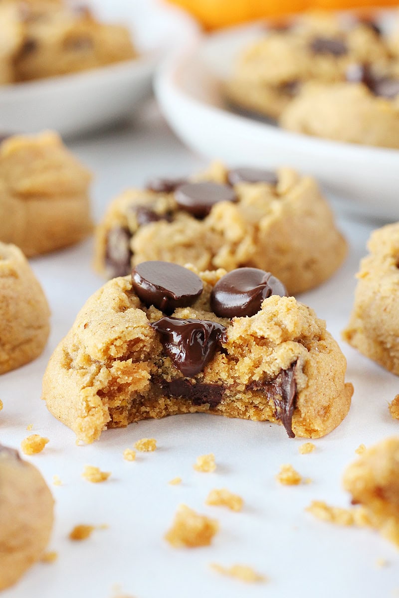 A bite taken out of a pumpkin chocolate chip cookie with melted chocolate.