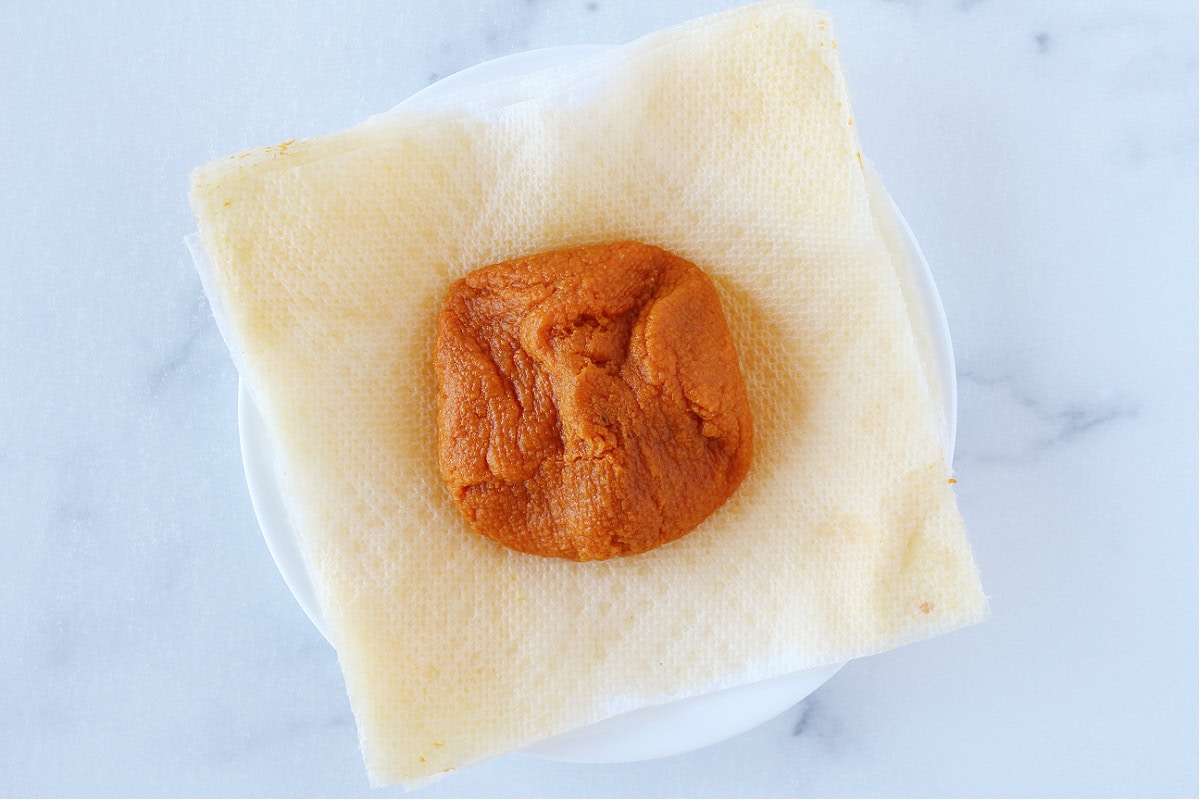 Pumpkin puree draining on a stack of paper towels on a plate.