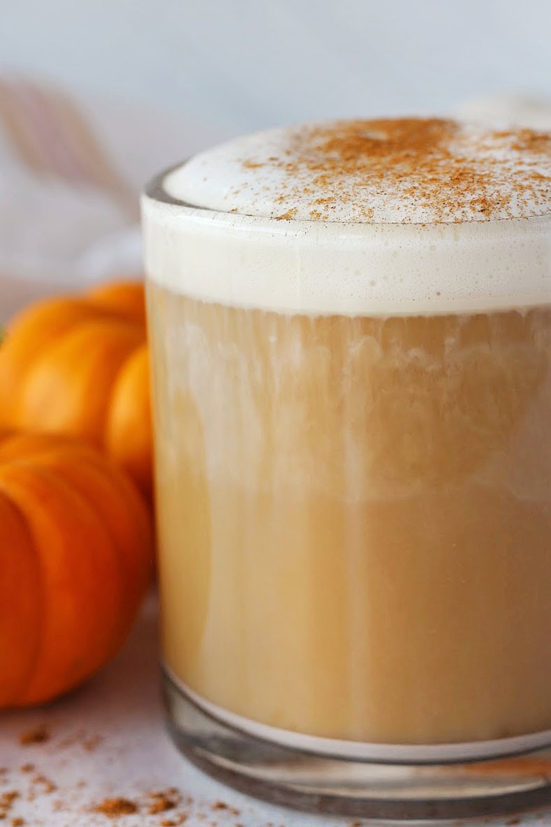 Tiny orange pumpkins beside a mug of homemade pumpkin spice latte.