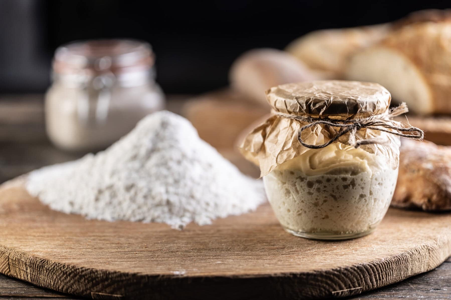 Sourdough starter in a glass jar with brown paper and twine on top.