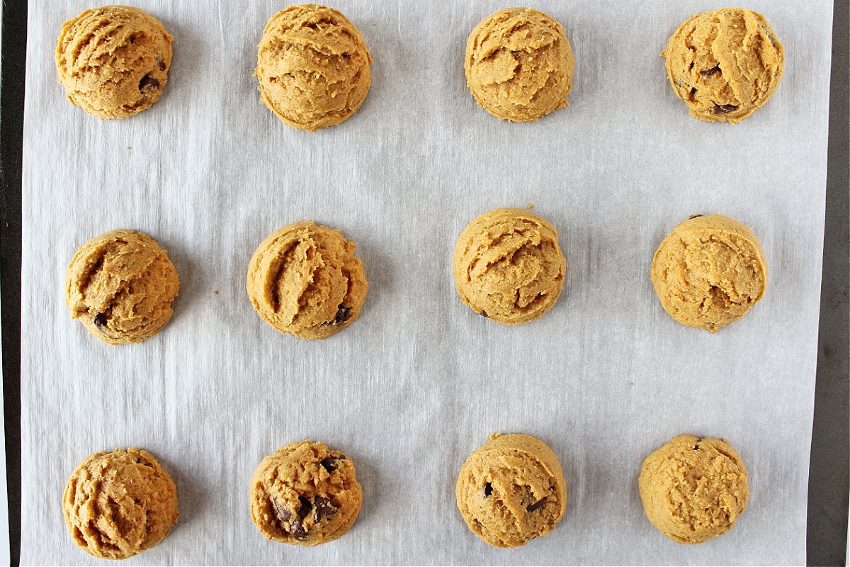 Twelve baked cookies on a baking sheet lined with parchment paper.
