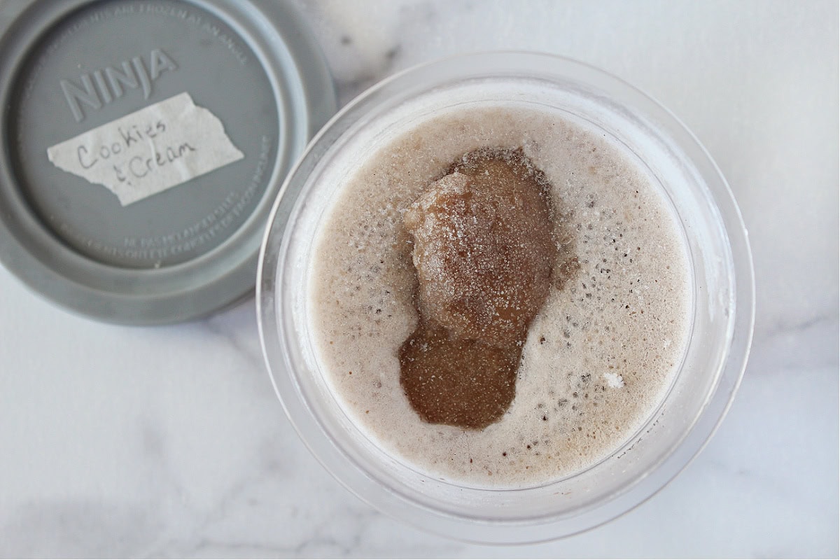 Frozen cookies and cream ice cream batter in Ninja Creami pint ready to be blended.