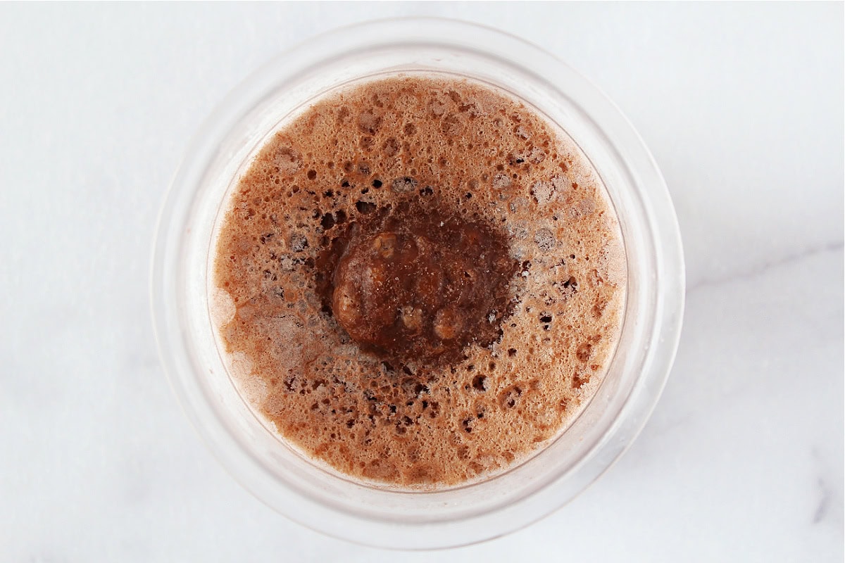 Frozen ice cream mix in clear Ninja Creami pint before blending.