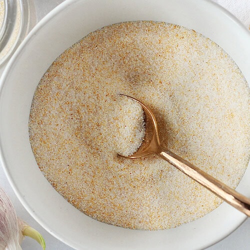 Copper spoon in a bowl of homemade garlic salt.