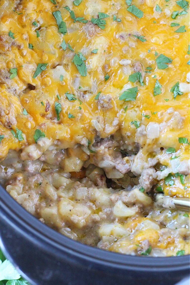 Cheesy casserole with ground beef and diced potatoes in a black Dutch oven.
