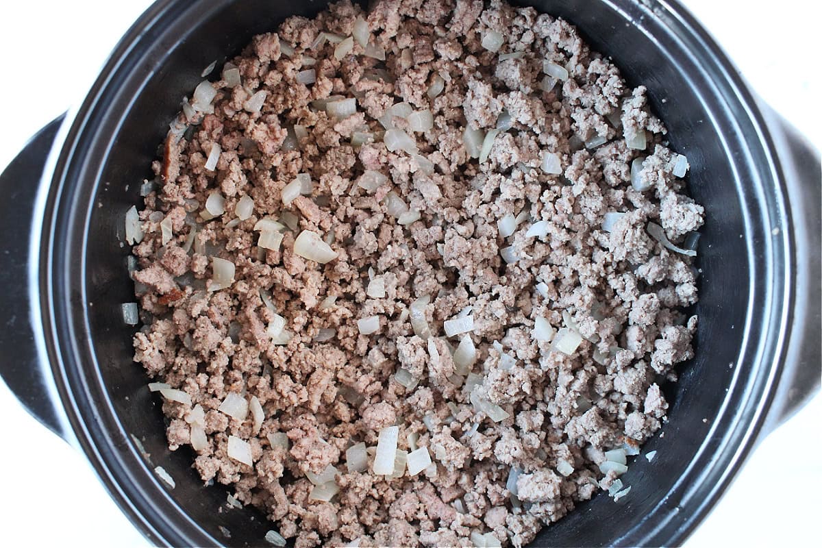 Browned ground beef and sautéed onions in a black Dutch oven.