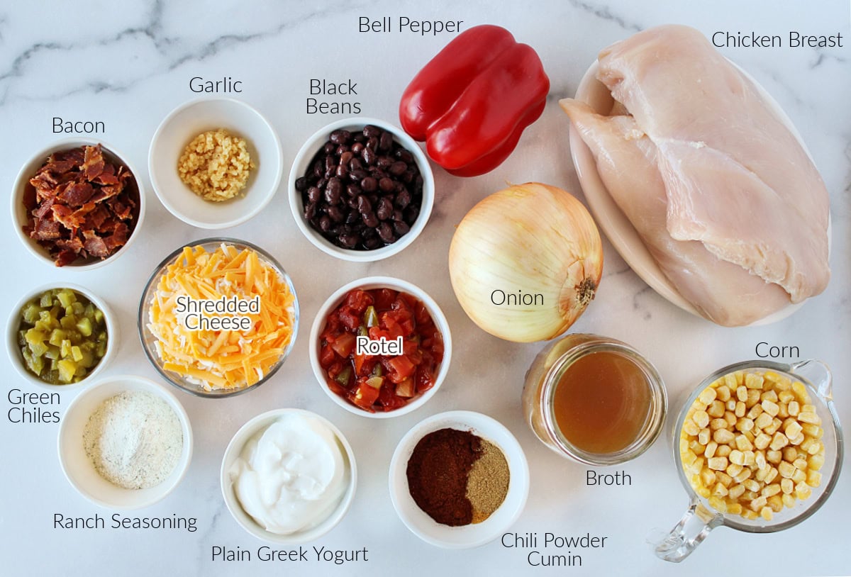 Labeled ingredients for crack chicken chili on a white marble countertop.