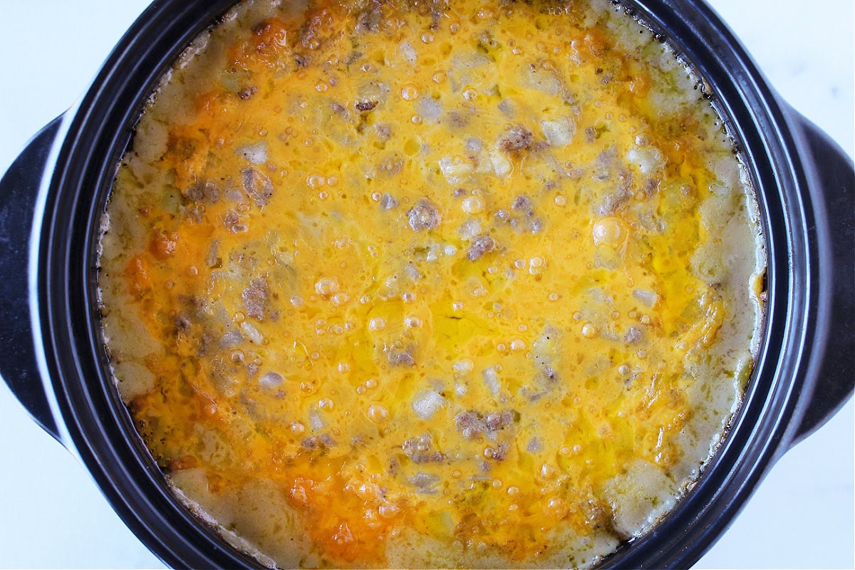 A baked casserole topped with melted cheese in a black Dutch oven.