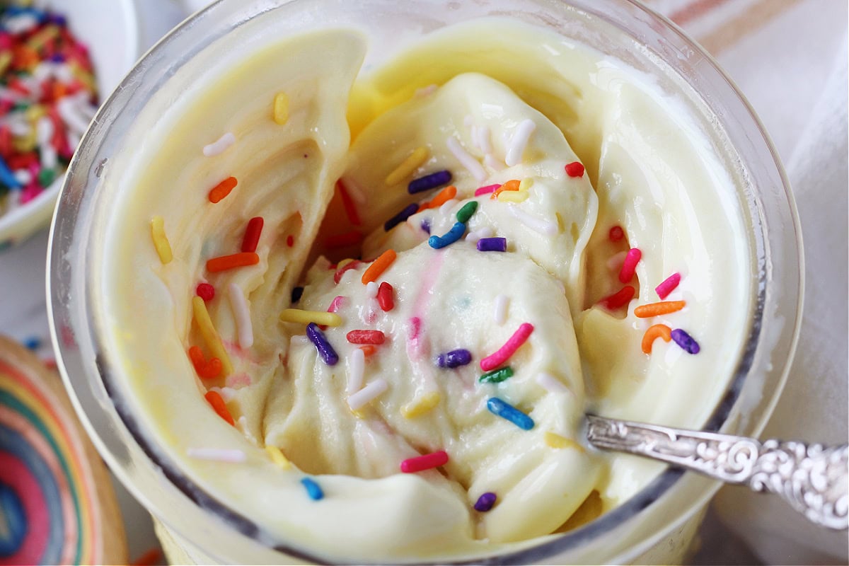 Rainbow sprinkles on cake batter ice cream in Ninja Creami pint.