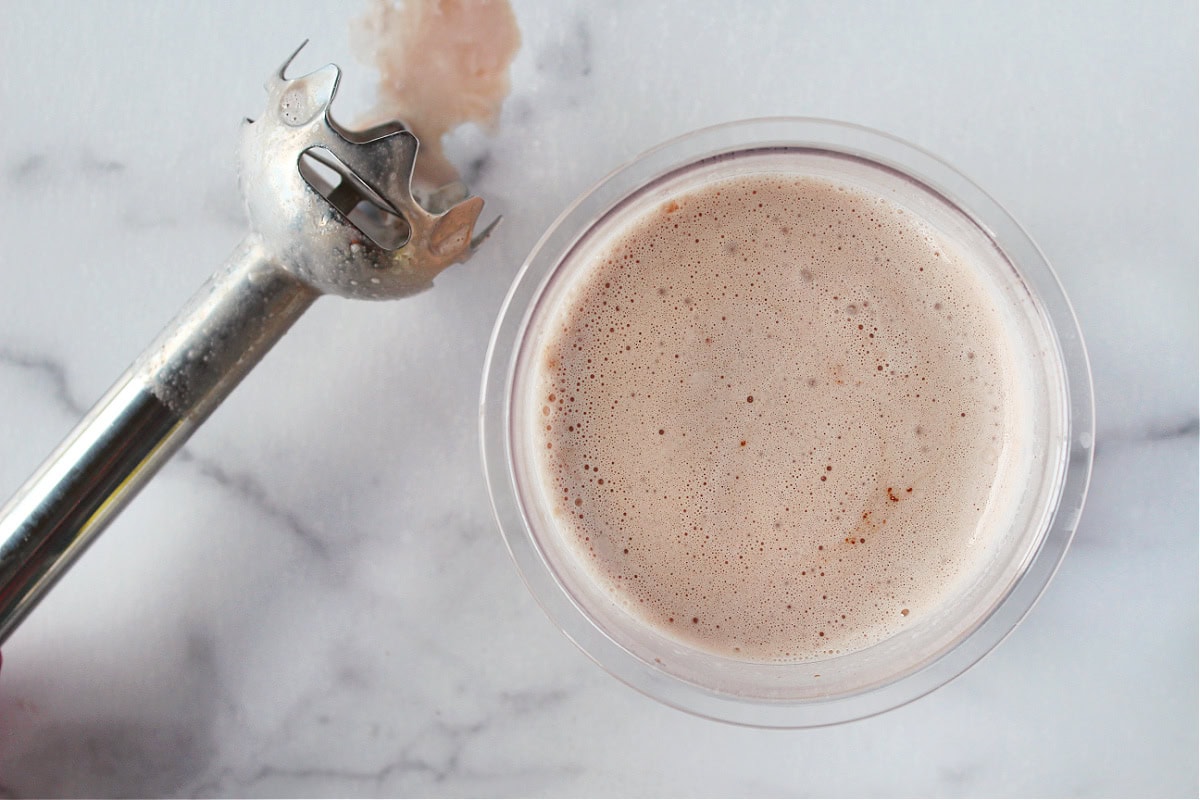 Immersion blender beside a Creami pint of chocolate ice cream batter.