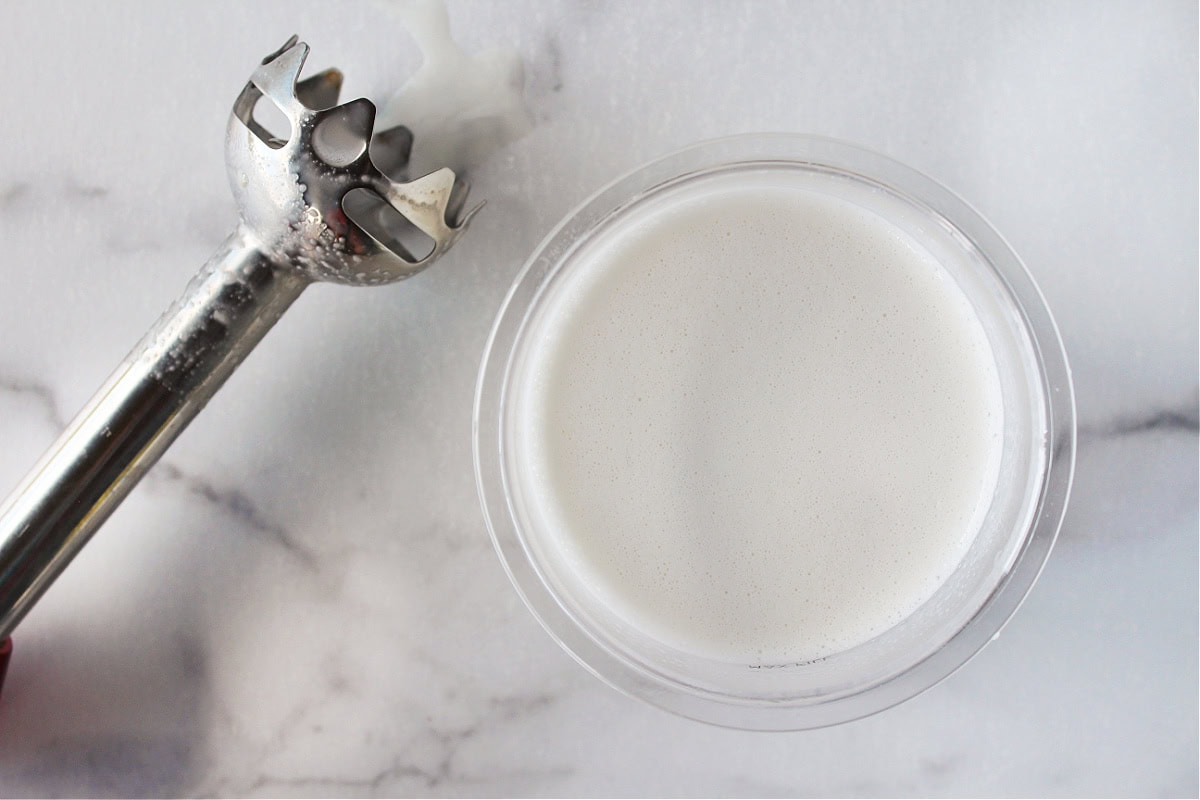 An immersion blender next to a vanilla ice cream batter.