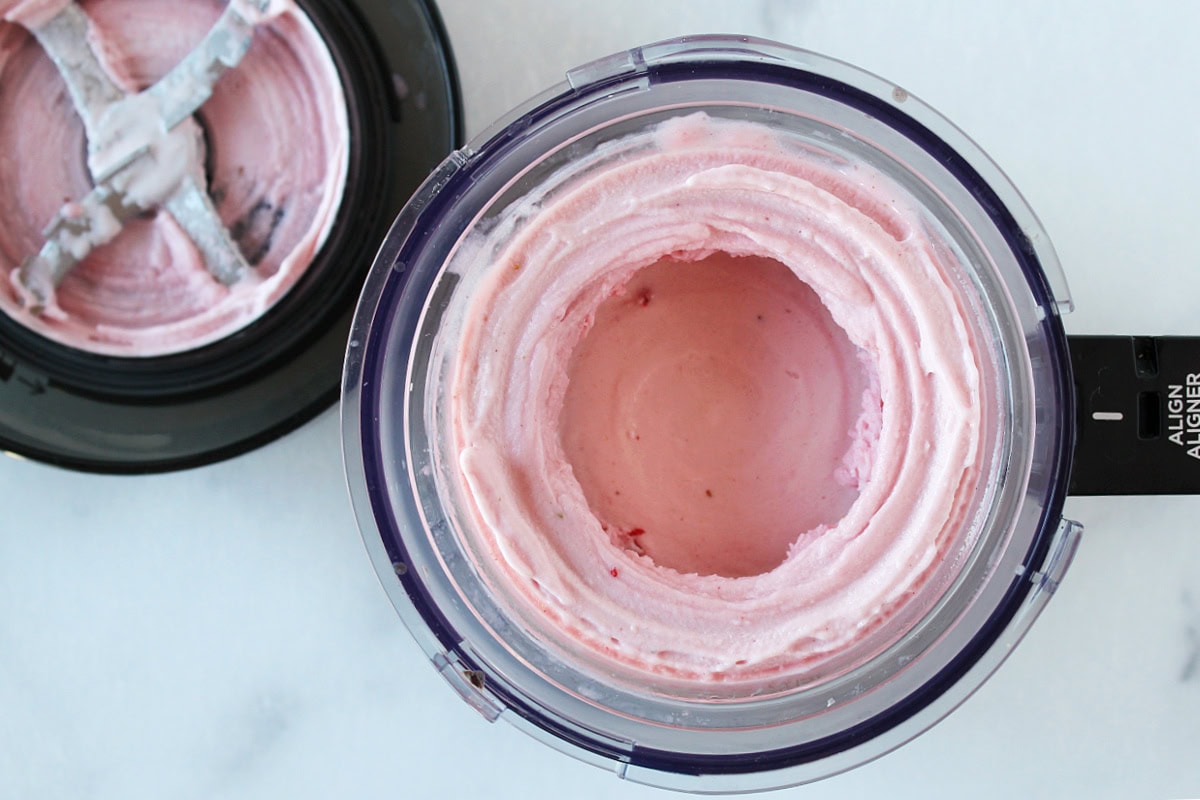 Blended strawberry ice cream in a Ninja Creami pint and outer bowl.