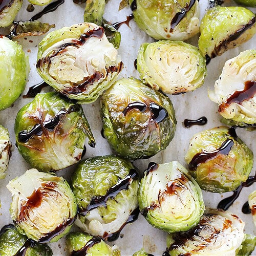 Roasted Brussel sprouts seasoned with garlic salt and black pepper drizzled with balsamic glaze.