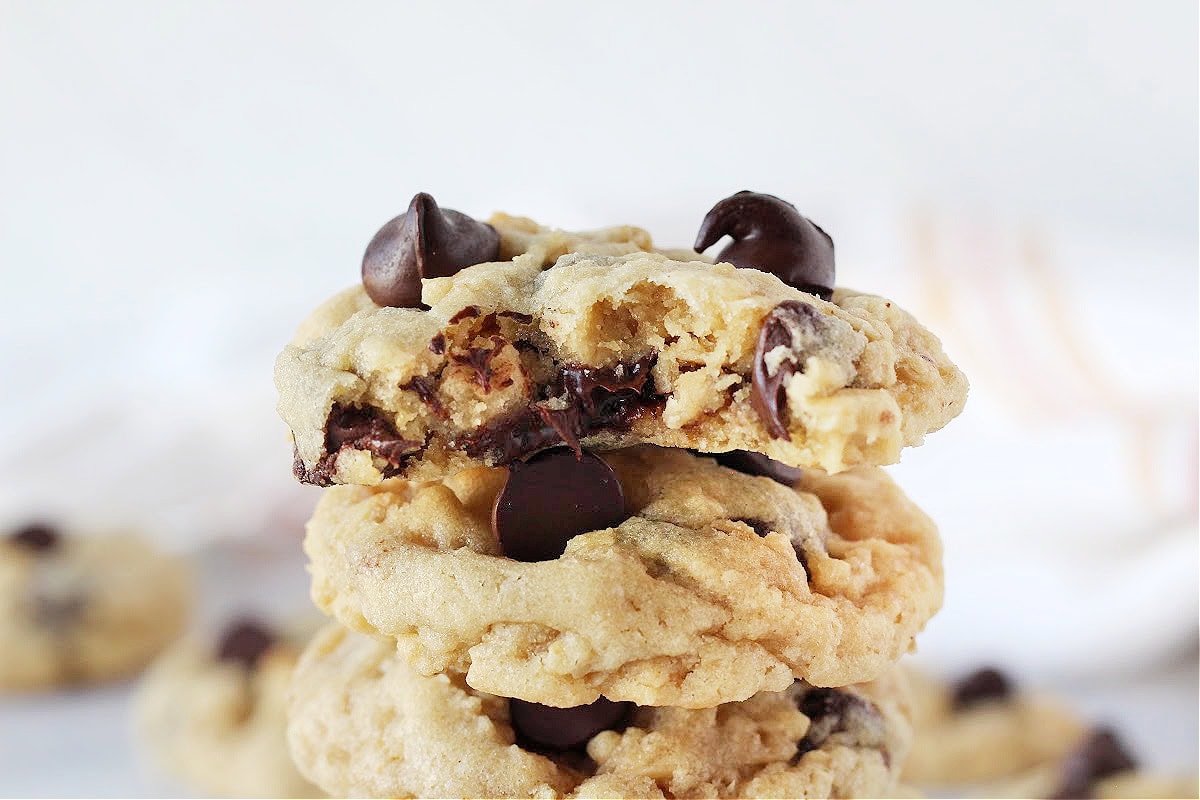 A bite taken out of an oatmeal chocolate chip cookie stacked on other cookies.