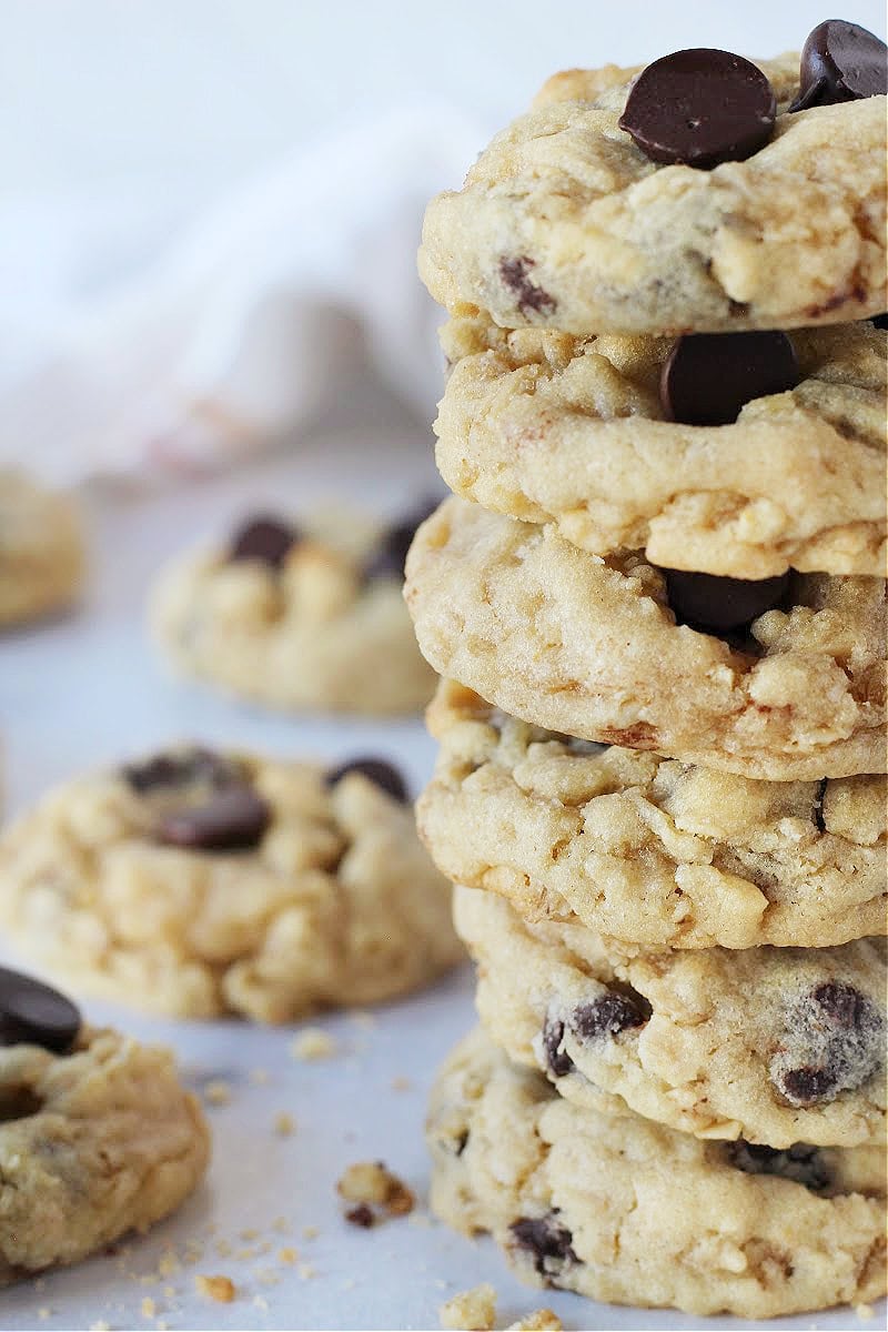 Six oatmeal chocolate chip cookies stacked on top of each other on a grey countertop.