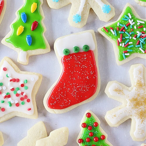 Christmas cutout sugar cookies with colorful icing on a white marble countertop.