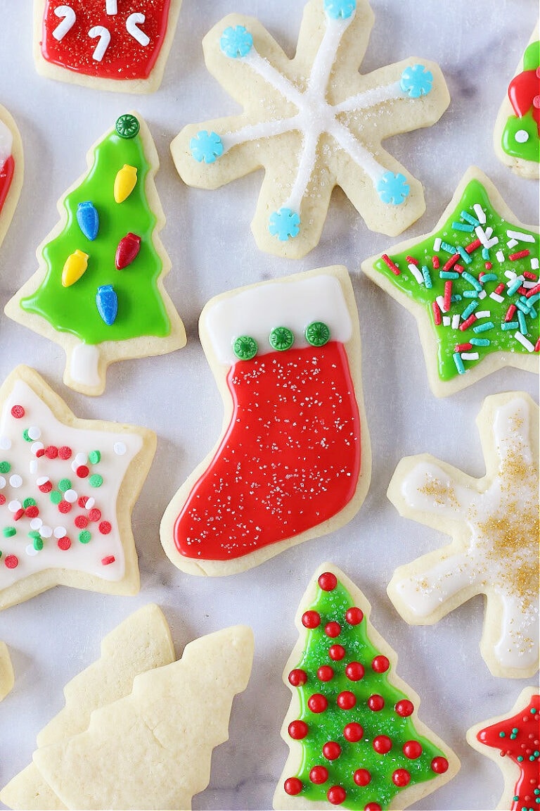 Christmas cutout sugar cookies with colorful icing on a white marble countertop.