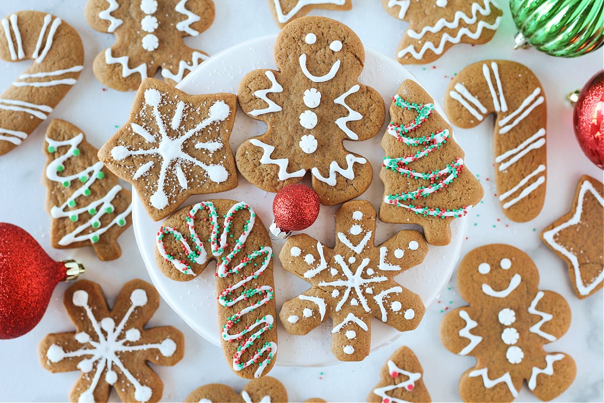 Decorated gingerbread cookies on a white stand with Christmas decorations.