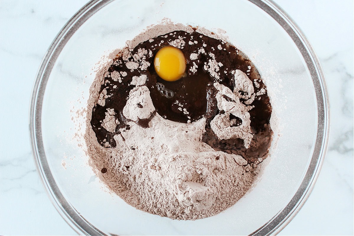 Egg, oil, and brownie mix in a glass mixing bowl.