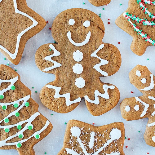 Homemade decorated gingerbread man cookie surrounded by other cut out shapes.