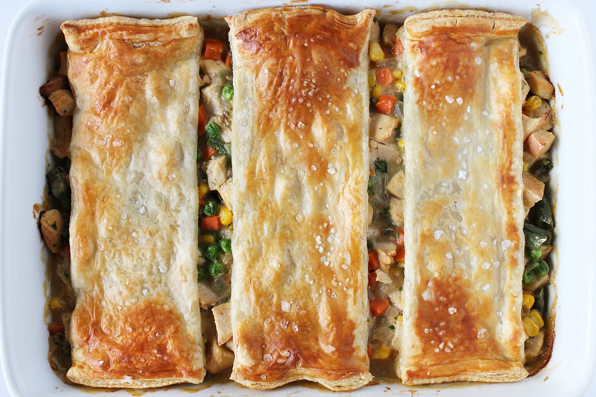 Golden brown puff pastry topped with flaked sea salt on pot pie mixture.