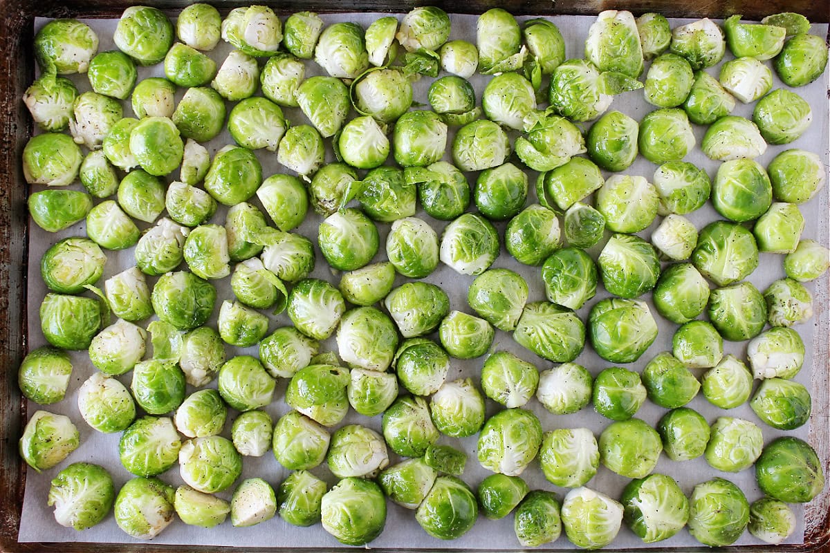 Halved Brussel sprouts coated in oil cut side down on a baking sheet.