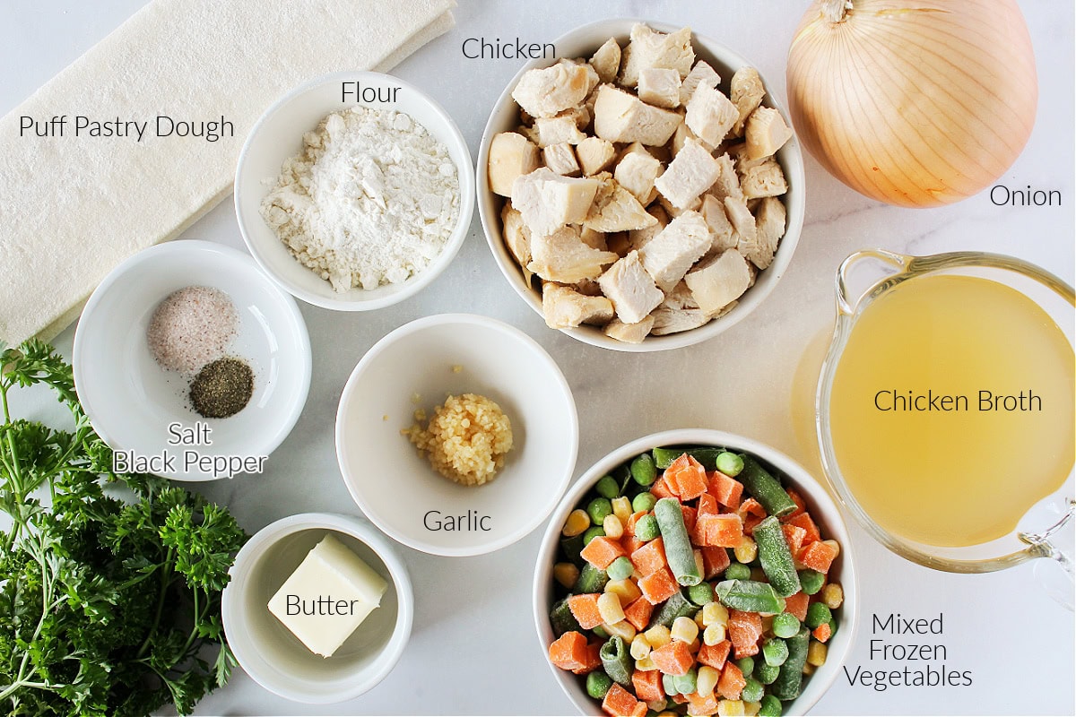 Labeled ingredients for easy chicken pot pie on a white marble countertop.