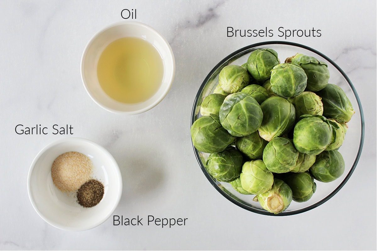 Labeled ingredients for balsamic Brussel sprouts on a white marble countertop.