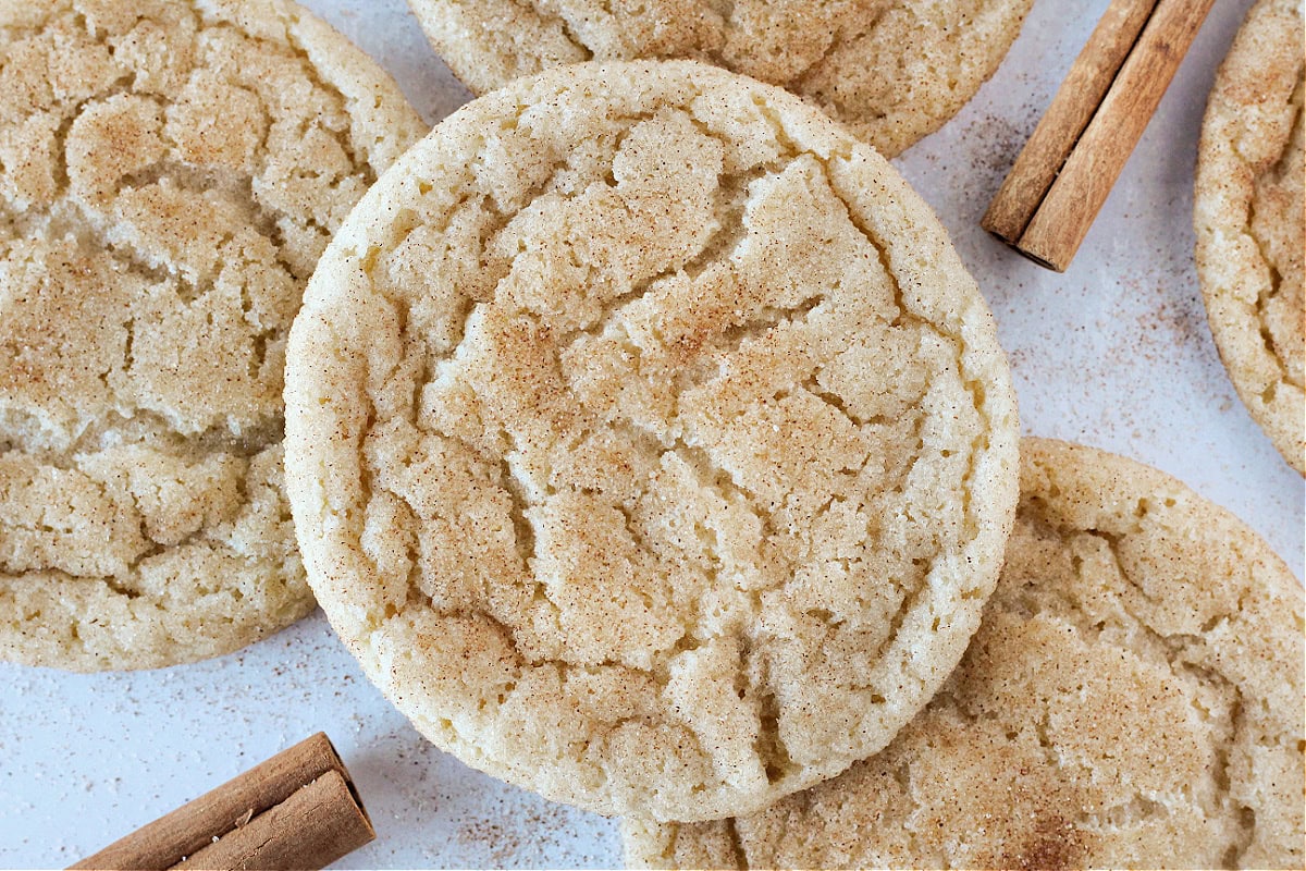 Snickerdoodle cookies on a white marble countertop with cinnamon and sugar.