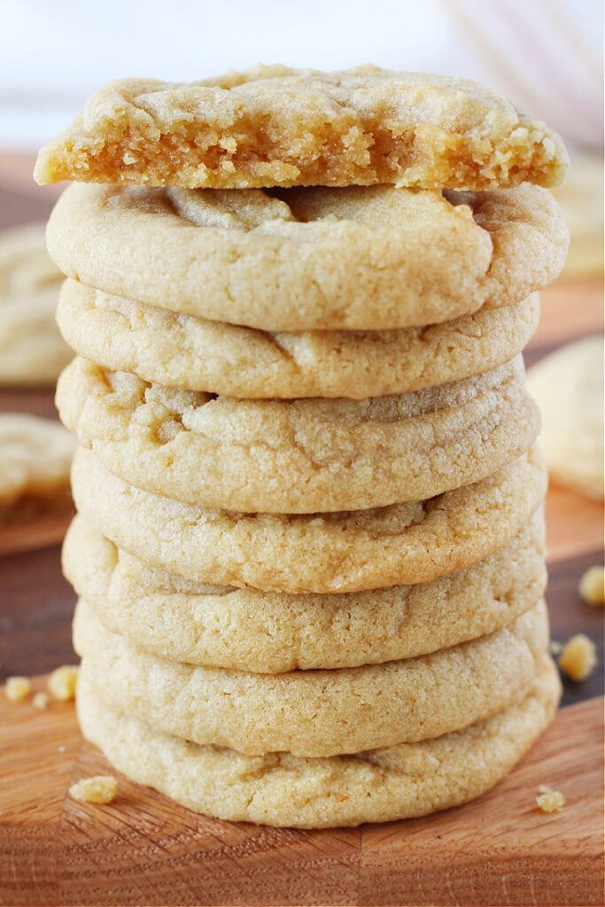 Brown butter cookies stacked high with half a cookie on top.