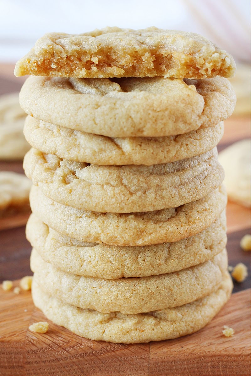 Brown butter cookies stacked high with half a cookie on top.