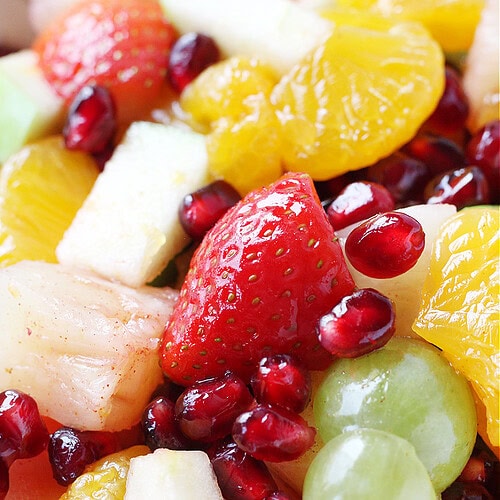 Orange cinnamon sauce covering sliced strawberries and grapes, pomegranate arils, apples, and mandarin orange slices.