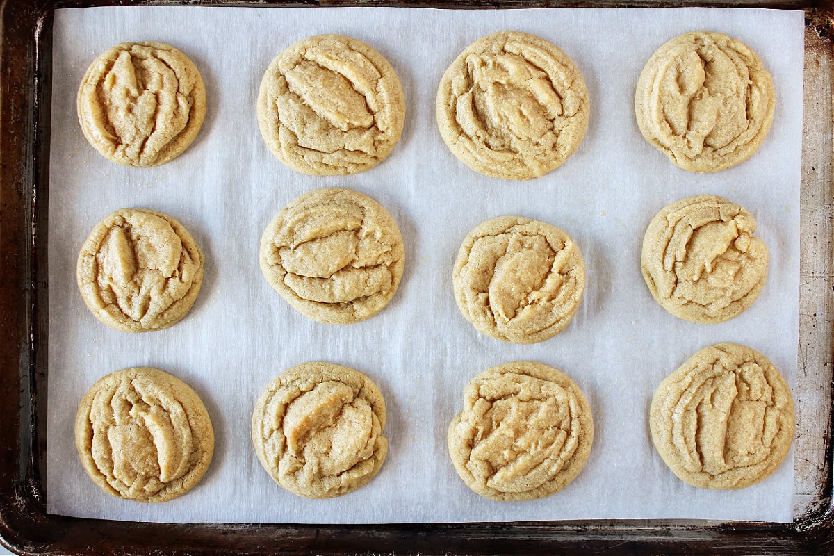 Twelve baked cookies on a parchment lined baking sheet.