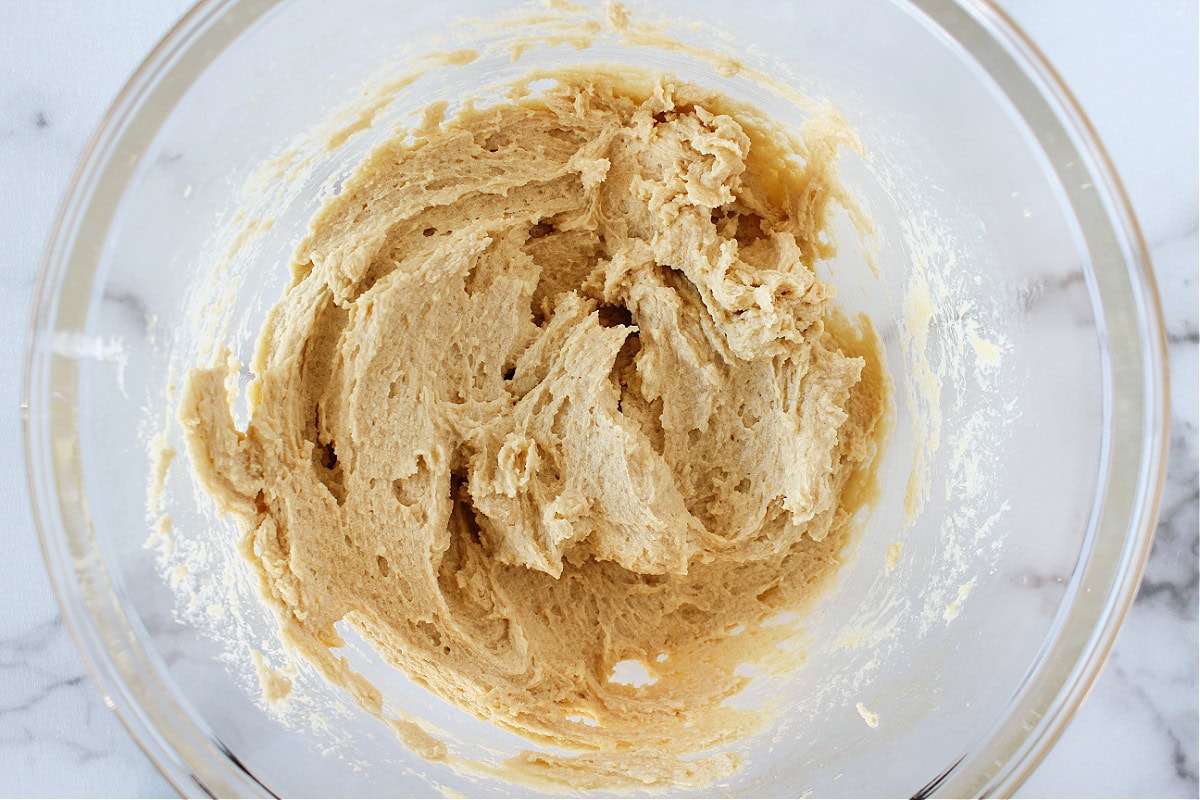 Fluffy wet batter for oatmeal cookies in a glass mixing bowl.