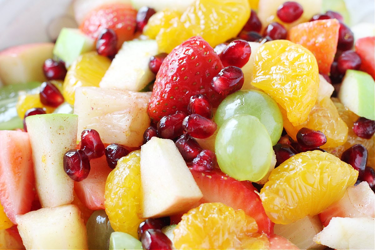 Sliced strawberries, apples, pomegranate arils, mandarin oranges, green grapes and pineapple.