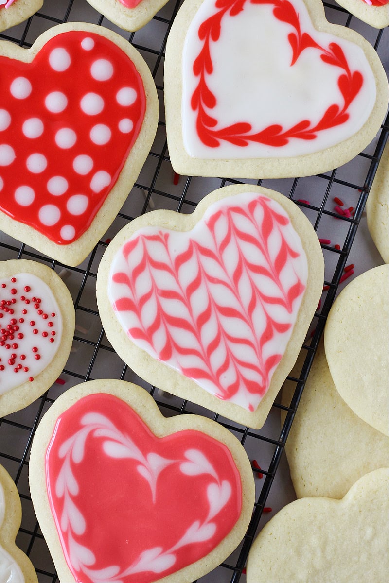 Beautifully decorated heart-shaped sugar cookies on a cooling rack.