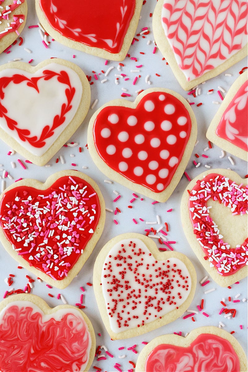 Red, pink, and white frosted heart-shaped sugar cookies with sprinkles.