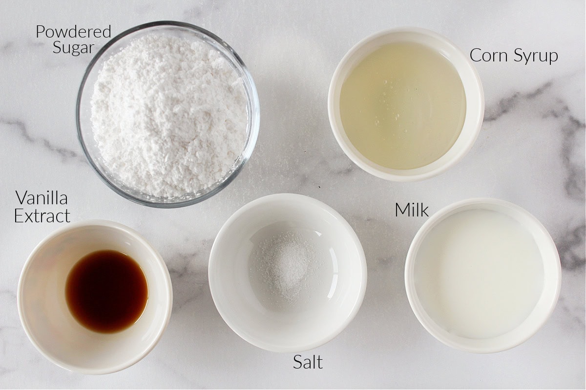 Labeled ingredients for powdered sugar frosting on a white marble countertop.