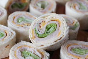 Turkey and cheese roll ups on a wooden cutting board.