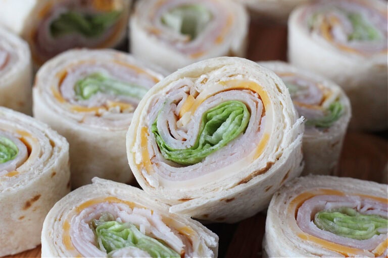 Turkey and cheese roll ups on a wooden cutting board.