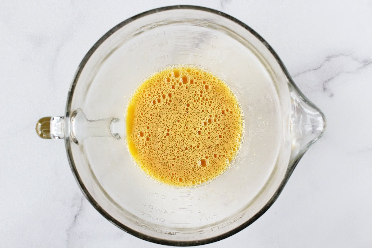 Eggs whisked in a glass mixing bowl.