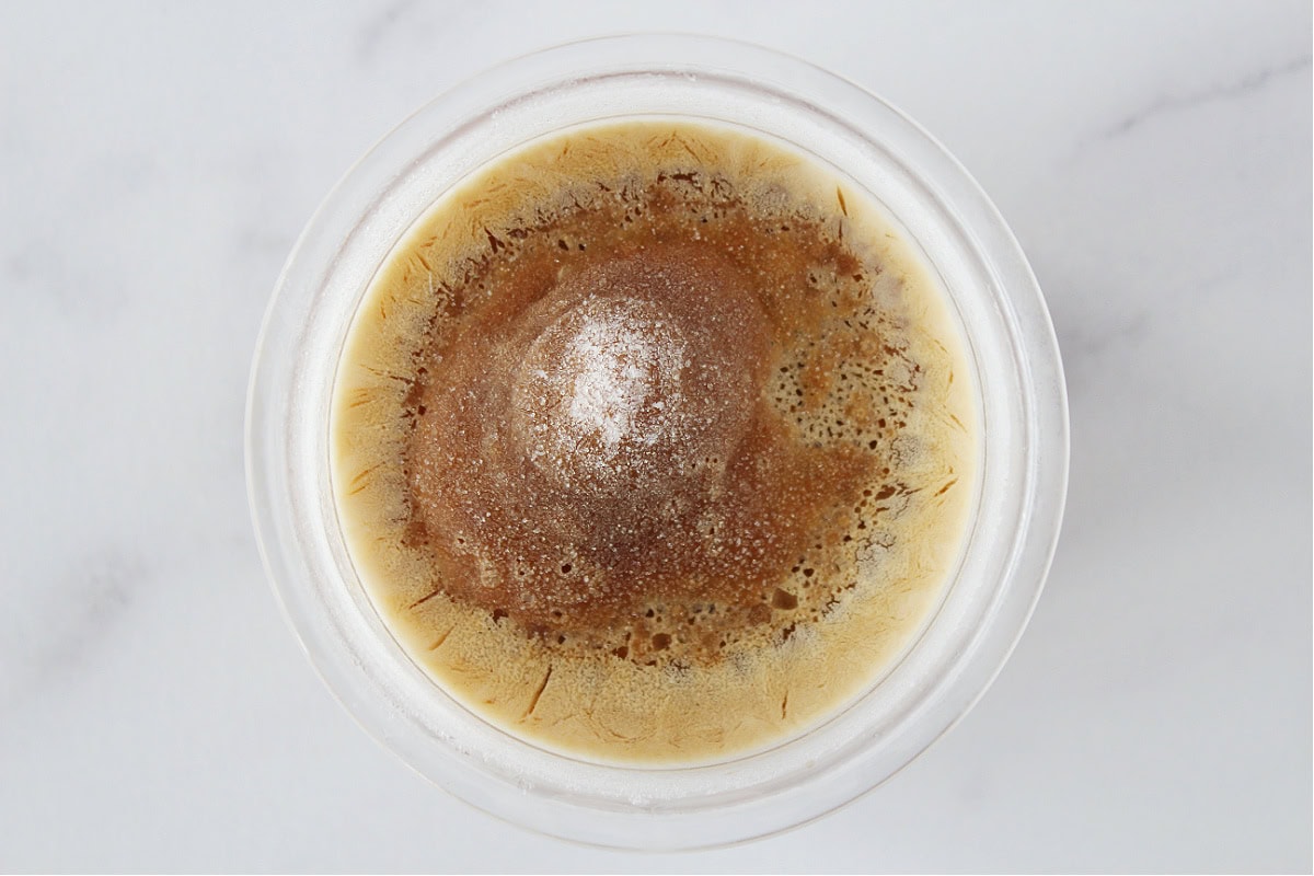 Frozen espresso ice cream batter in a Ninja Creami plastic container.