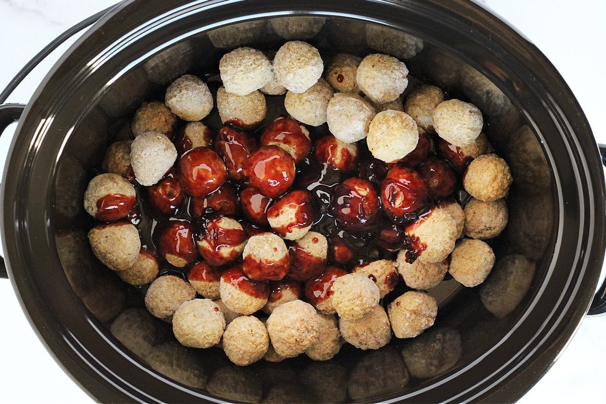 Frozen turkey meatballs in a crock pot with raspberry balsamic sauce poured over the top.