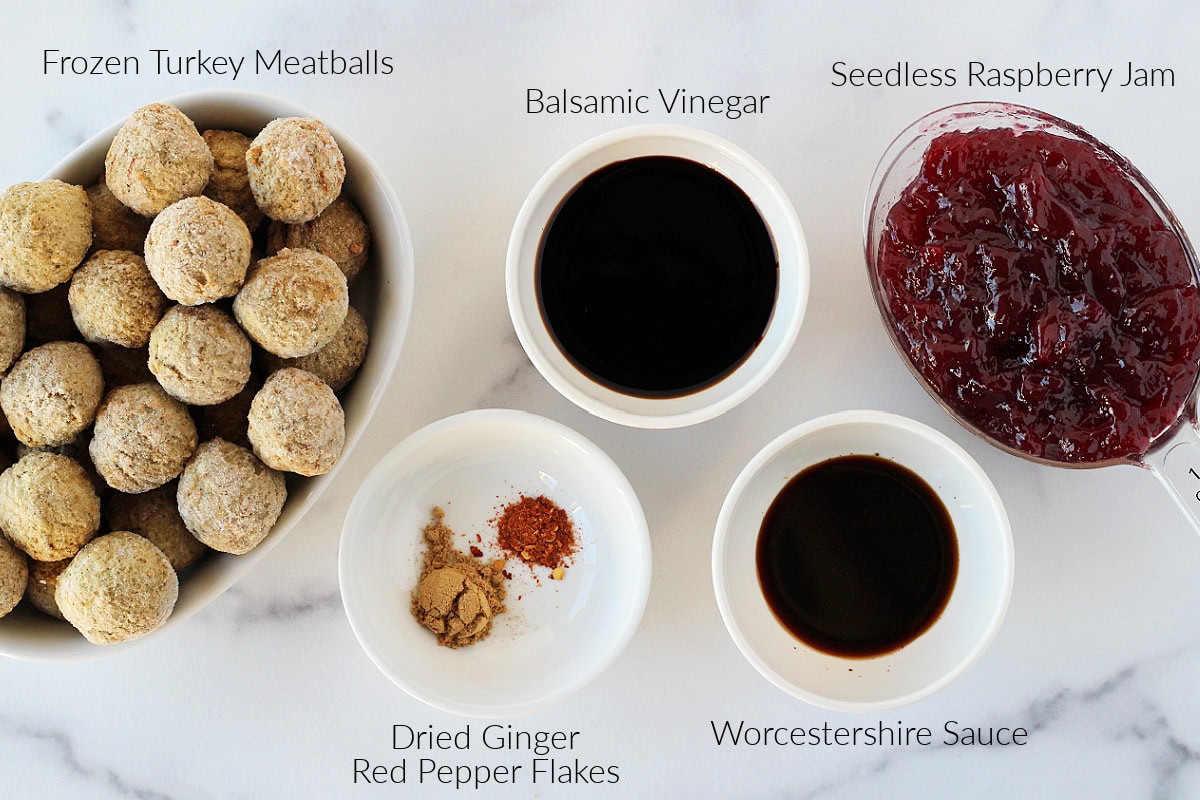 Labeled ingredients for raspberry balsamic crockpot meatballs on a white marble countertop.