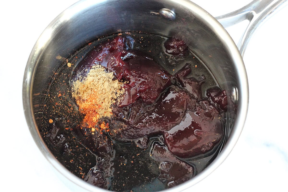Seedless raspberry jam, dried ginger, red pepper flakes, and balsamic vinegar in a saucepan.