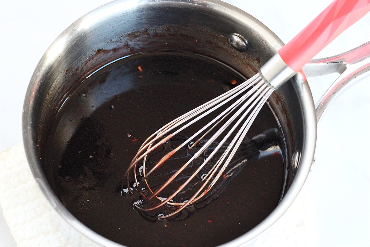 A whisk in a saucepan of raspberry and balsamic vinegar.