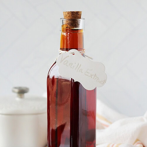 A tall bottle with a cork lid filled with homemade vanilla extract.