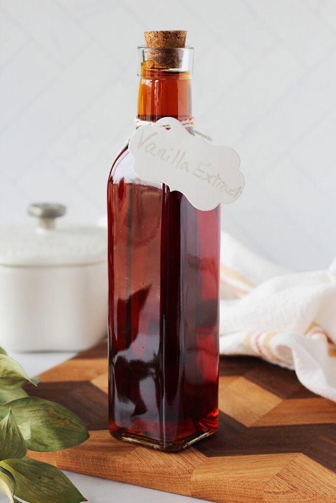 A tall bottle with a cork lid filled with homemade vanilla extract.
