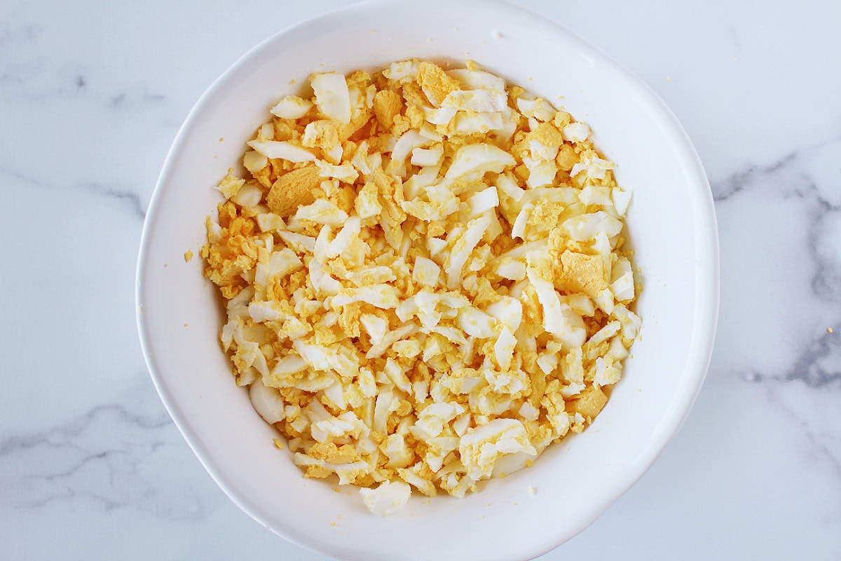 Chopped hard boiled eggs in a white mixing bowl.